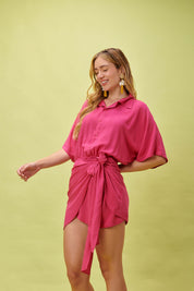 A pink Tropicana Breeze dress with a knot detail, part of DESIRE DENIM's women's tropical summer apparel collection.